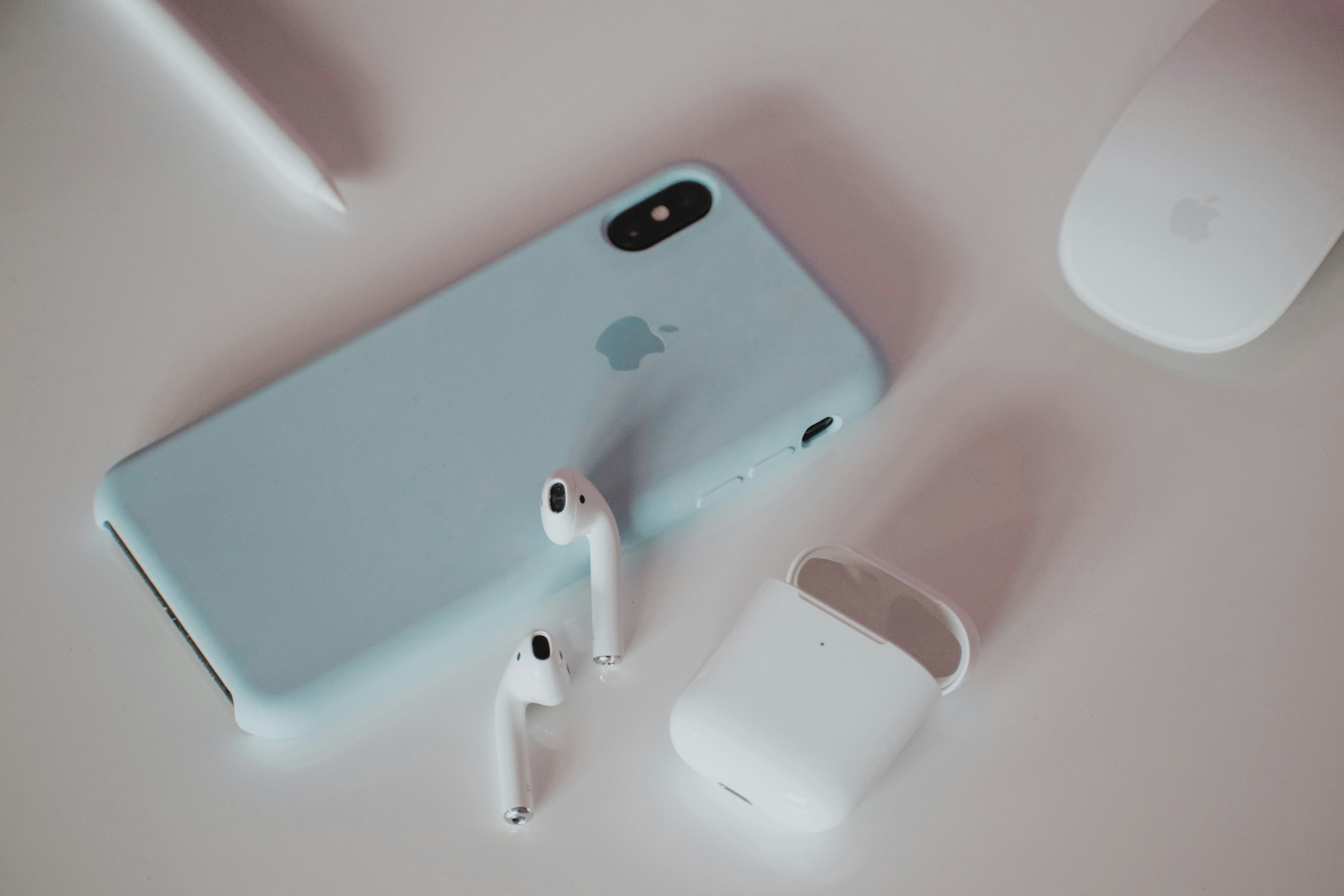 An iPhone with AirPods and a case laid out on a pale background